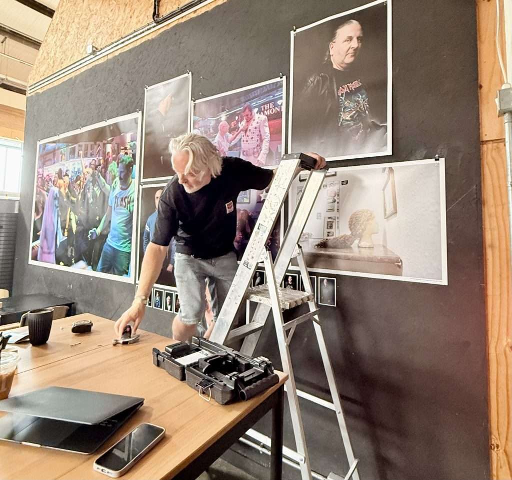 Brian up a ladder putting the diamond exhibition photos up in 92 degrees
