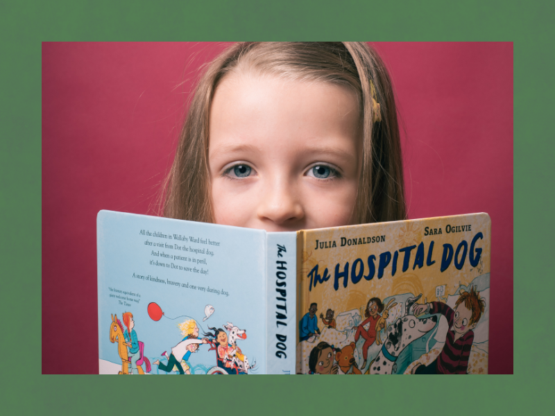 A young girl reading 'The Hospital Dog' by Julia Donaldson.