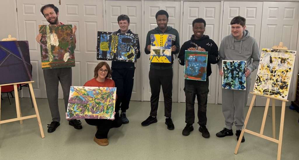 Jade holds up art work with 5 young artists