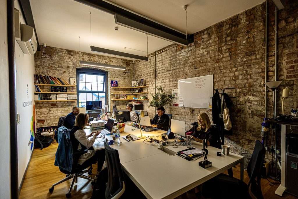 Inclusive Companies team working in their office at Baltic Creative with bare brick walls and regenerated industrial feel